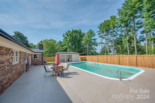 view of swimming pool with an outdoor structure and a patio