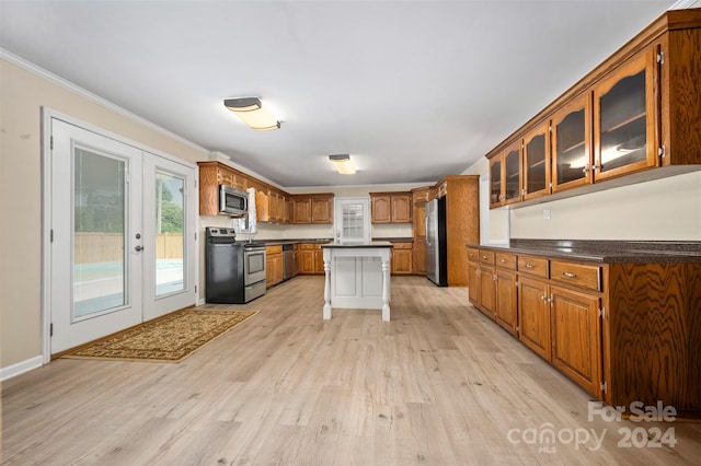 kitchen with light hardwood / wood-style flooring, ornamental molding, a kitchen bar, a center island, and stainless steel appliances