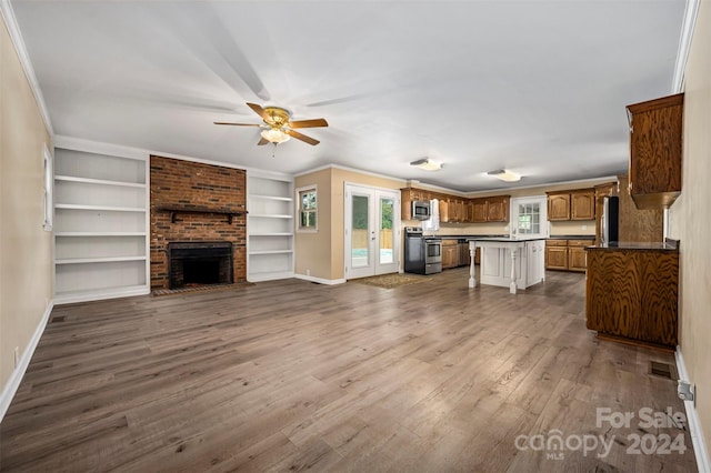 unfurnished living room featuring ceiling fan, a fireplace, brick wall, and wood-type flooring