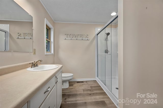 bathroom with toilet, vanity, hardwood / wood-style floors, a textured ceiling, and a shower with shower door