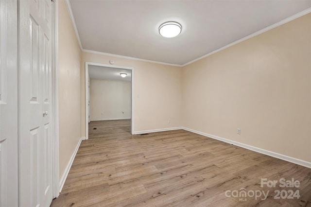 spare room featuring crown molding and light hardwood / wood-style floors