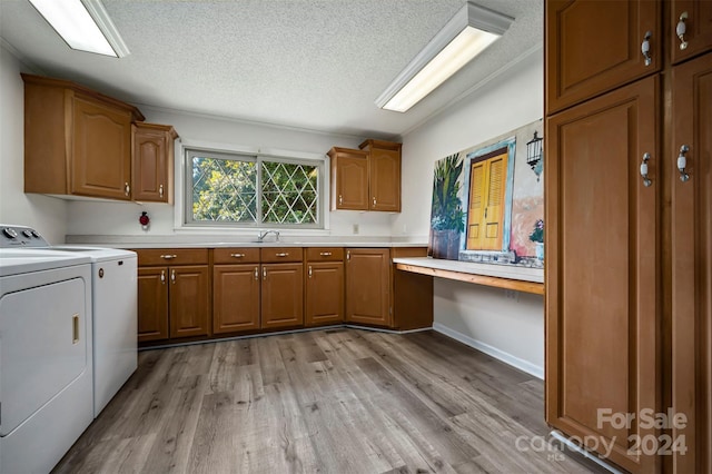 laundry area with light hardwood / wood-style floors, washer and clothes dryer, sink, cabinets, and a textured ceiling