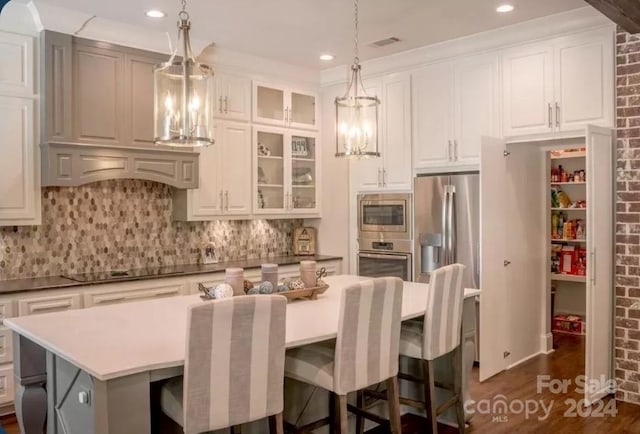 kitchen featuring decorative backsplash, dark hardwood / wood-style floors, appliances with stainless steel finishes, pendant lighting, and a center island