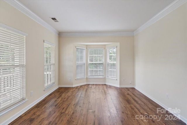 spare room featuring dark wood-type flooring, plenty of natural light, and crown molding