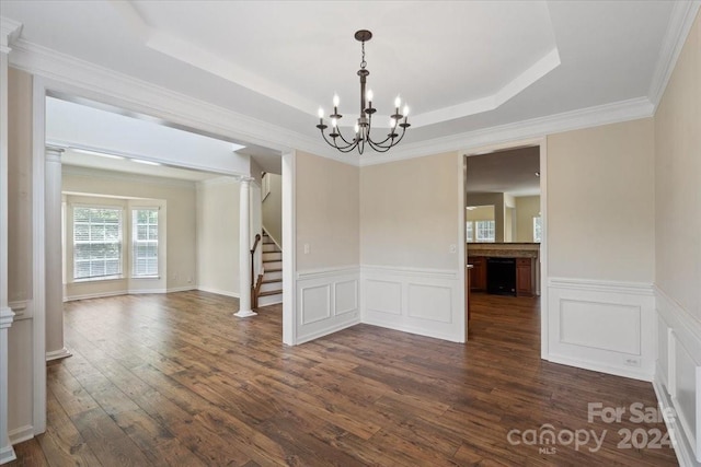 unfurnished dining area featuring ornate columns, dark hardwood / wood-style flooring, ornamental molding, a notable chandelier, and a raised ceiling