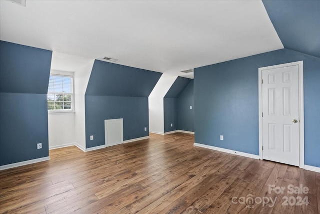 additional living space with vaulted ceiling and hardwood / wood-style floors