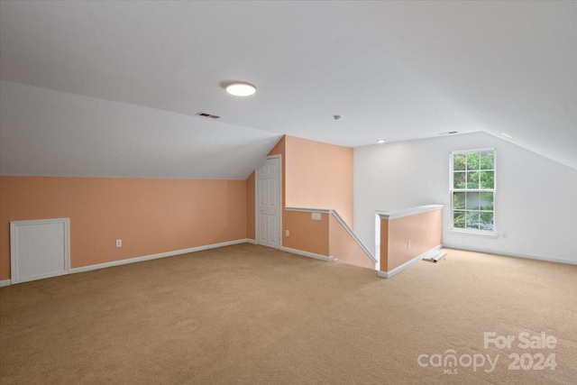 additional living space with vaulted ceiling and light carpet