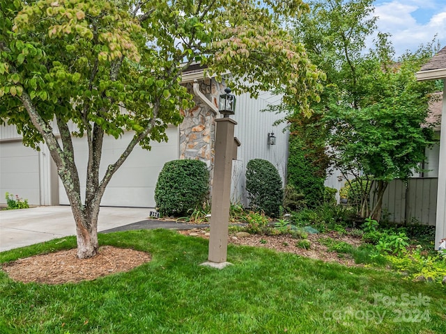 view of side of home featuring a garage, driveway, a lawn, and fence