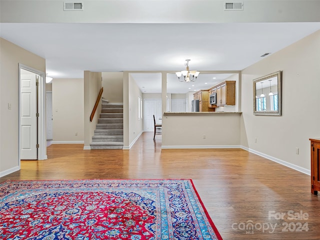 unfurnished living room with stairs, visible vents, and light wood-style floors