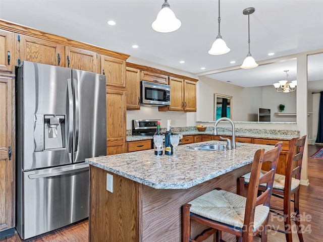 kitchen featuring appliances with stainless steel finishes, brown cabinetry, a sink, and dark wood-type flooring