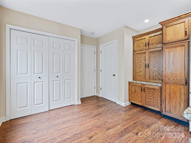 unfurnished bedroom featuring recessed lighting, a closet, baseboards, and wood finished floors