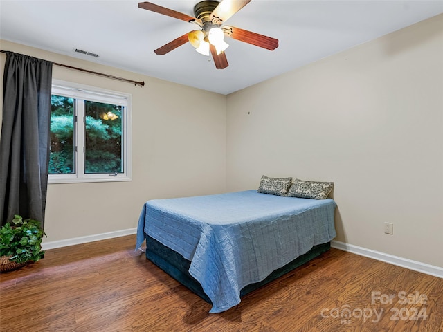 bedroom featuring visible vents, wood finished floors, a ceiling fan, and baseboards