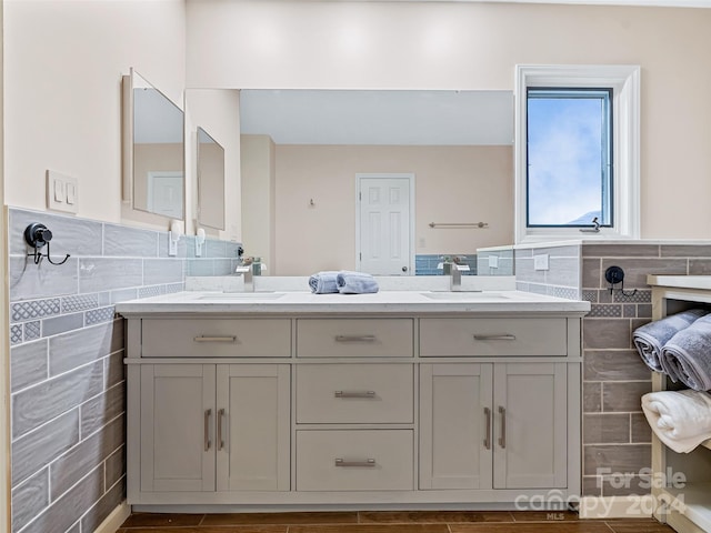 bathroom featuring double vanity, a wainscoted wall, tile walls, and a sink