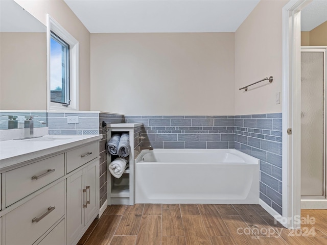 full bathroom featuring a stall shower, vanity, tile walls, and wood finished floors