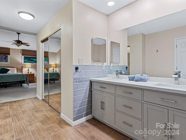 ensuite bathroom featuring wood tiled floor, a sink, tile walls, and ensuite bath