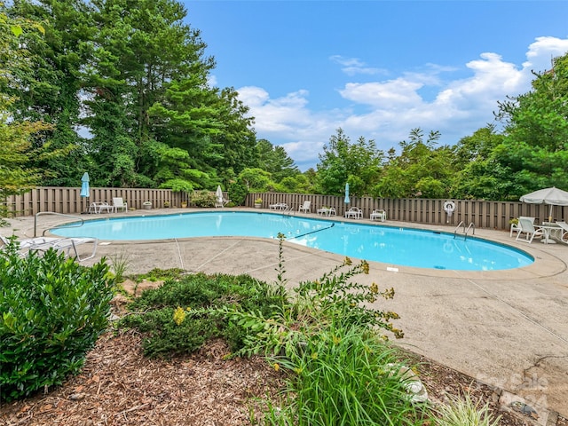 pool with a patio area and fence