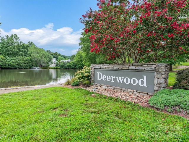 community sign with a water view and a lawn