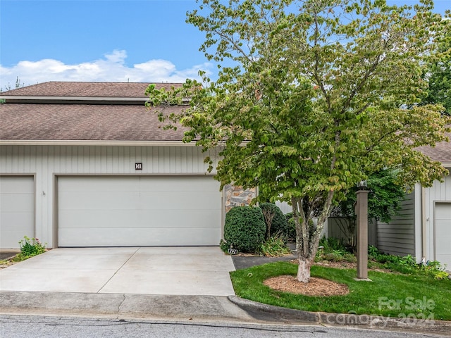 view of property featuring concrete driveway and roof with shingles