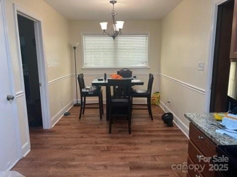 dining space with dark hardwood / wood-style flooring and a notable chandelier