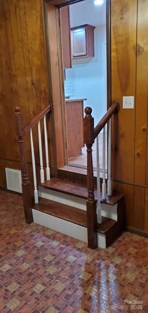 stairs featuring wood walls