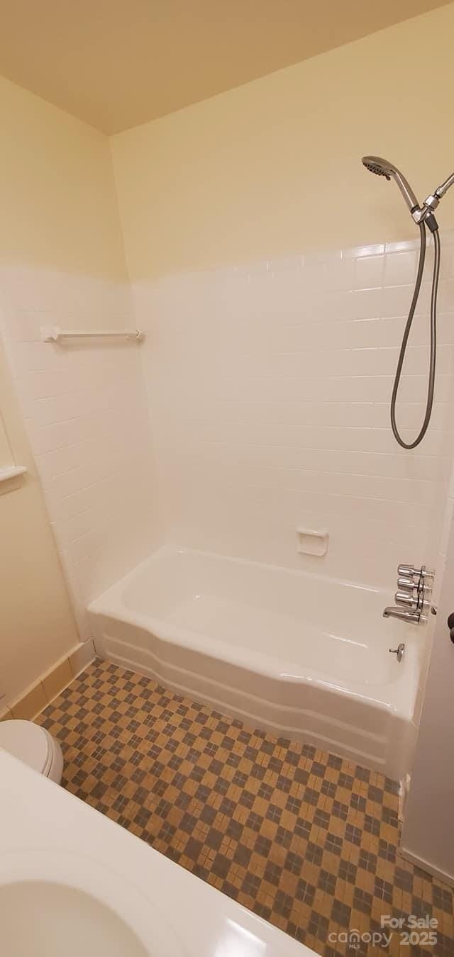 bathroom with bathtub / shower combination and toilet