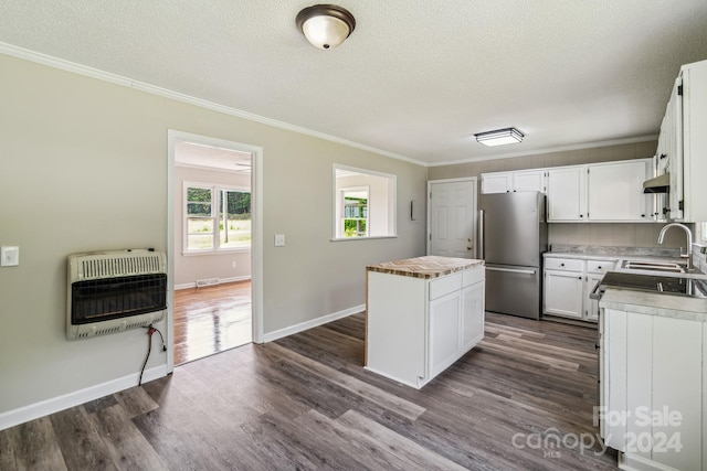 kitchen with white cabinetry, a center island, heating unit, and stainless steel fridge