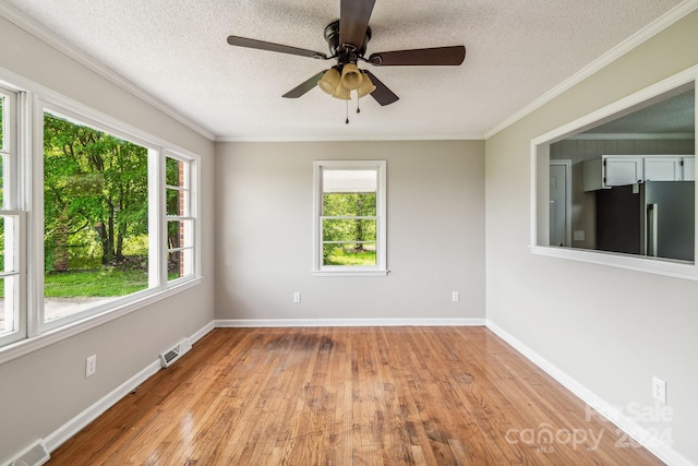 empty room with ornamental molding, ceiling fan, a textured ceiling, and light hardwood / wood-style floors