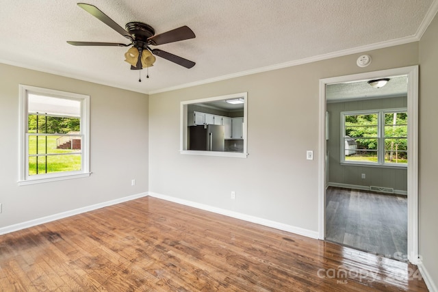 empty room with ornamental molding, wood-type flooring, and a textured ceiling