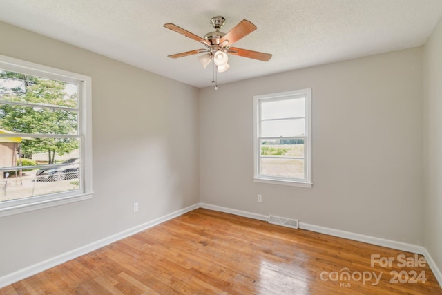 empty room with ceiling fan, a textured ceiling, and light hardwood / wood-style flooring