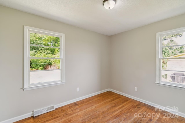 empty room with hardwood / wood-style flooring and a textured ceiling