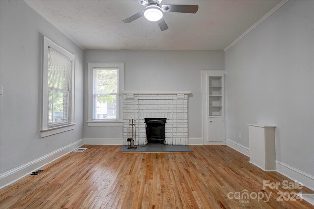 unfurnished living room with a fireplace, light hardwood / wood-style flooring, ceiling fan, and crown molding