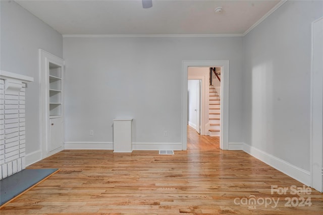 spare room featuring light hardwood / wood-style flooring, ornamental molding, and built in shelves