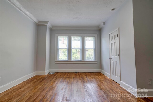 spare room with hardwood / wood-style floors and ornamental molding