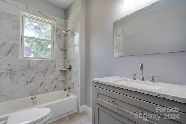 full bathroom featuring tile patterned floors, tiled shower / bath, vanity, and toilet