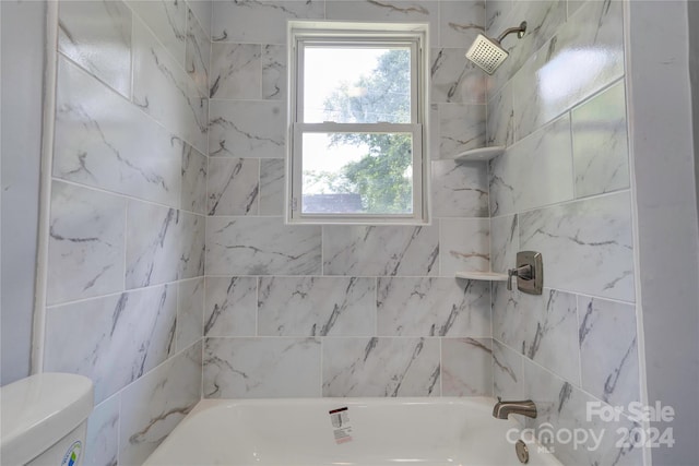 bathroom featuring tiled shower / bath and toilet