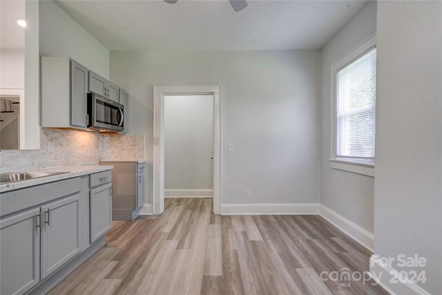 kitchen with light hardwood / wood-style floors, backsplash, gray cabinets, and ceiling fan