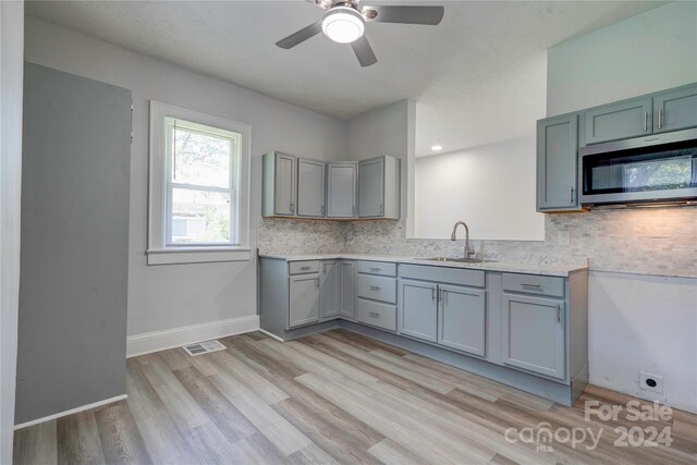 kitchen with sink, light wood-type flooring, tasteful backsplash, and ceiling fan