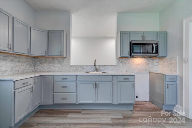 kitchen featuring sink, light hardwood / wood-style flooring, and decorative backsplash