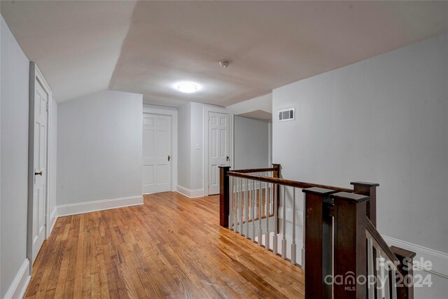 corridor featuring vaulted ceiling and light hardwood / wood-style flooring