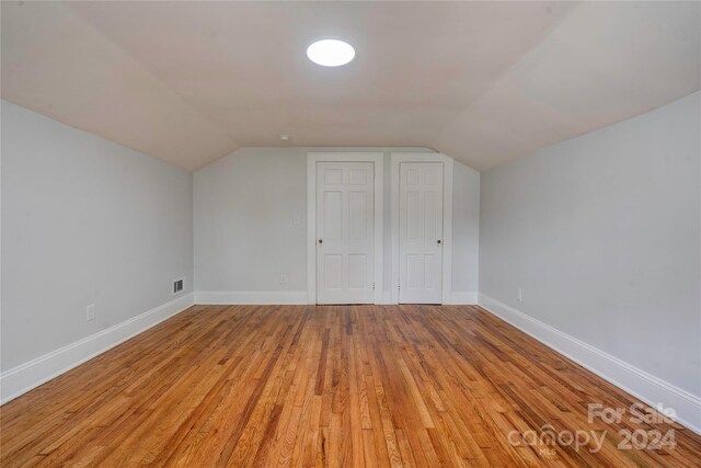 additional living space with vaulted ceiling and light hardwood / wood-style flooring