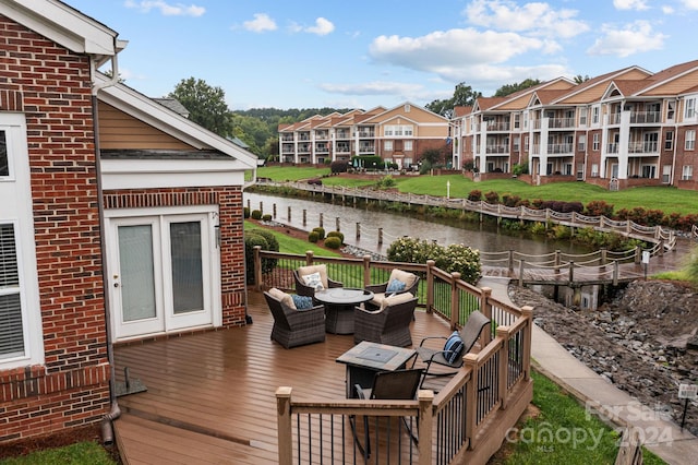 wooden deck featuring a water view and a fire pit