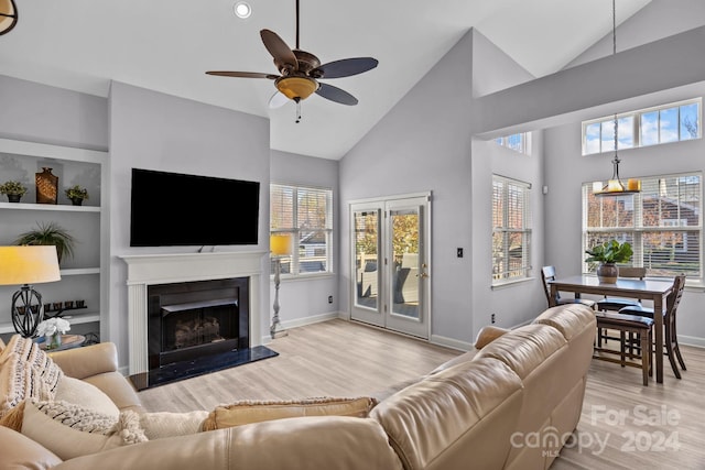 living room featuring high vaulted ceiling, built in features, light hardwood / wood-style floors, and ceiling fan