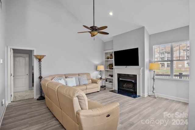 living room featuring light hardwood / wood-style floors, high vaulted ceiling, and ceiling fan