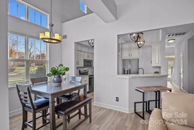 dining area with light wood-type flooring, a notable chandelier, and sink