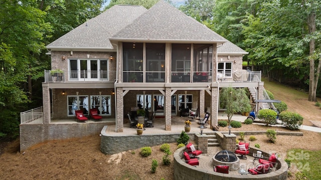 rear view of property with a patio, an outdoor fire pit, and a sunroom