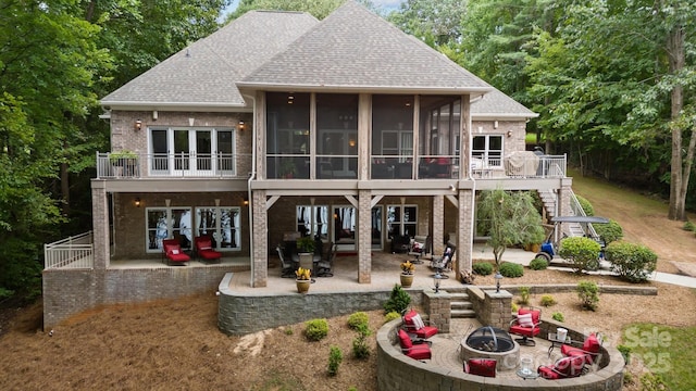 rear view of property with a patio, a sunroom, and an outdoor fire pit