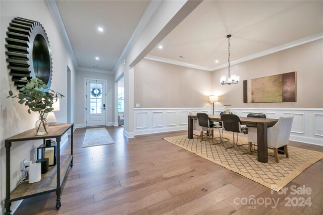 foyer entrance featuring ornamental molding, wood-type flooring, and a notable chandelier