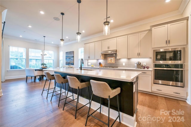 kitchen featuring pendant lighting, a spacious island, appliances with stainless steel finishes, and light wood-type flooring