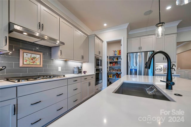 kitchen with crown molding, backsplash, appliances with stainless steel finishes, pendant lighting, and sink