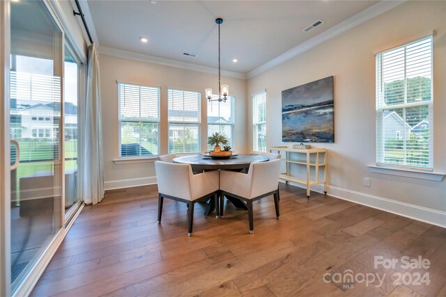 dining space featuring wood-type flooring, a healthy amount of sunlight, and ornamental molding